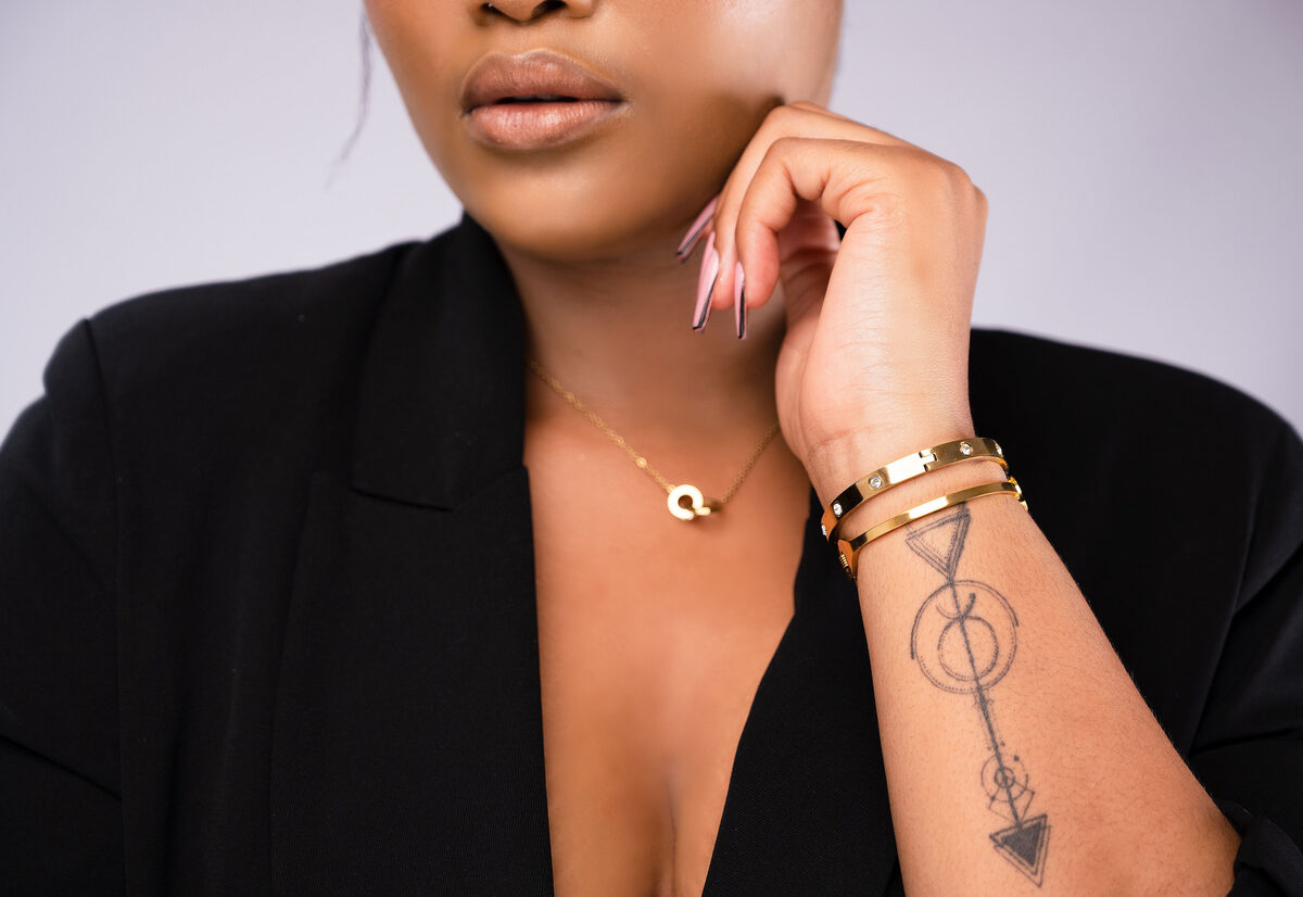 Gold initial pendant necklace layered with stacked gold bangles.